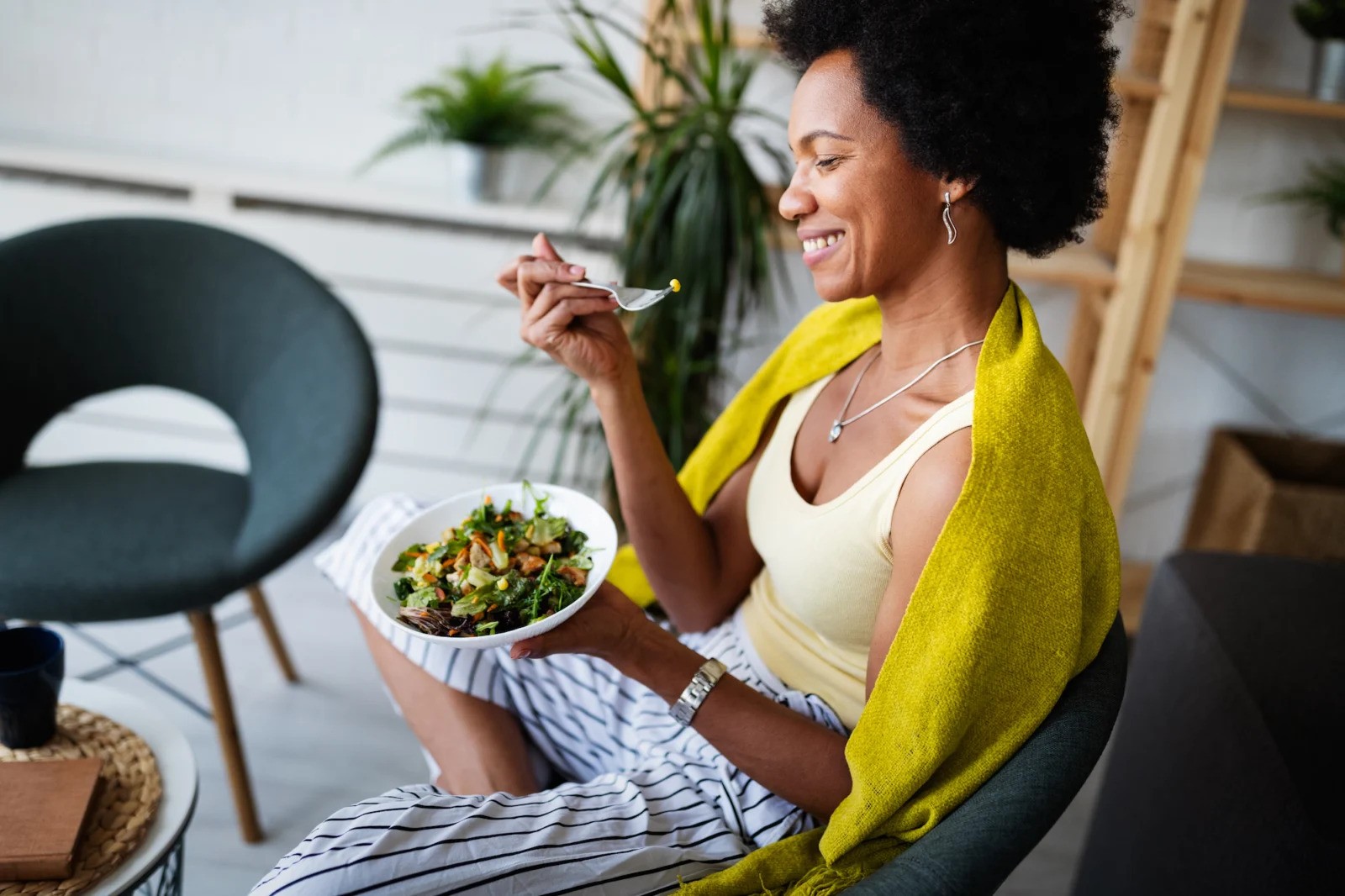 Beautiful African American woman eating vegetable salad at home.; Shutterstock ID 1820691038